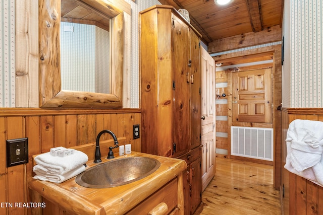 bathroom featuring wooden walls, visible vents, wooden ceiling, wood finished floors, and vanity