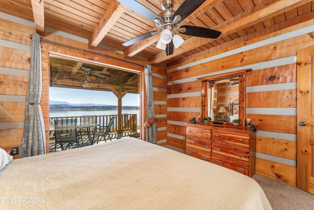 bedroom featuring access to exterior, a water view, wood ceiling, and wooden walls