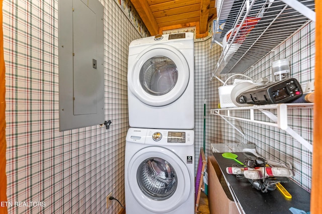 clothes washing area with laundry area, electric panel, and stacked washing maching and dryer