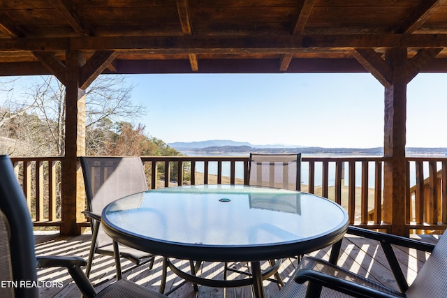 wooden deck featuring outdoor dining space and a water and mountain view