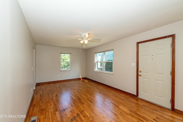 spare room featuring a ceiling fan, visible vents, light wood-style flooring, and baseboards