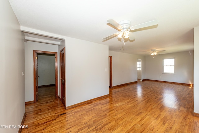 spare room with light wood-type flooring, ceiling fan, and baseboards