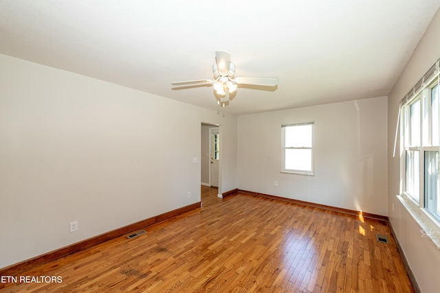 empty room featuring a wealth of natural light, baseboards, visible vents, and light wood finished floors