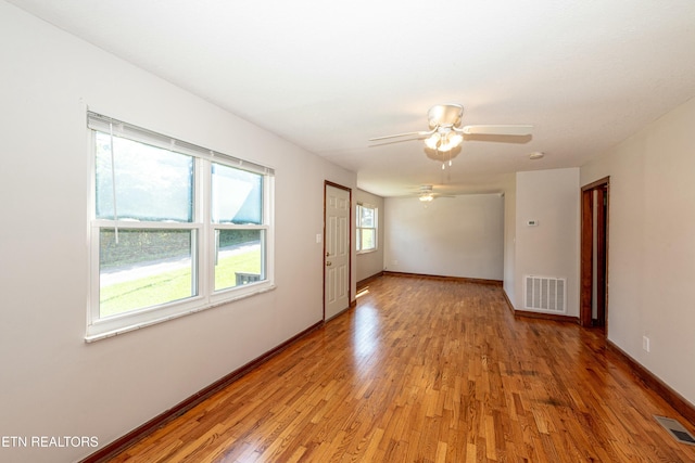 spare room featuring light wood-type flooring, visible vents, and baseboards