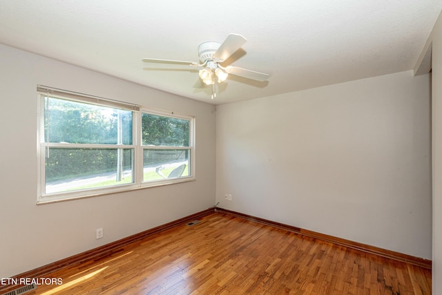 spare room with light wood finished floors, baseboards, visible vents, and a ceiling fan