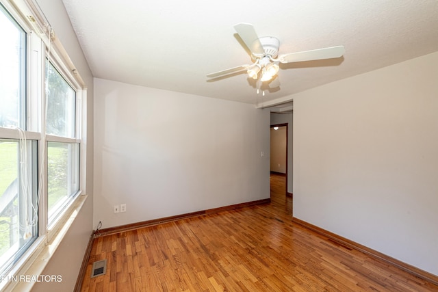 spare room with baseboards, a wealth of natural light, visible vents, and light wood-style floors