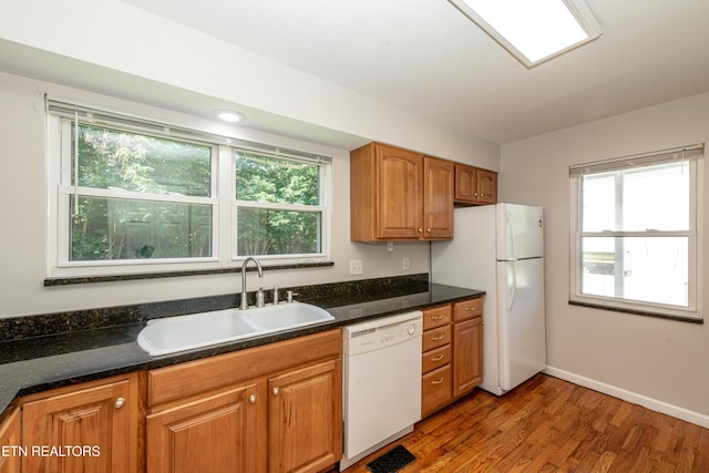 kitchen with dark countertops, white appliances, light wood-style floors, and a sink