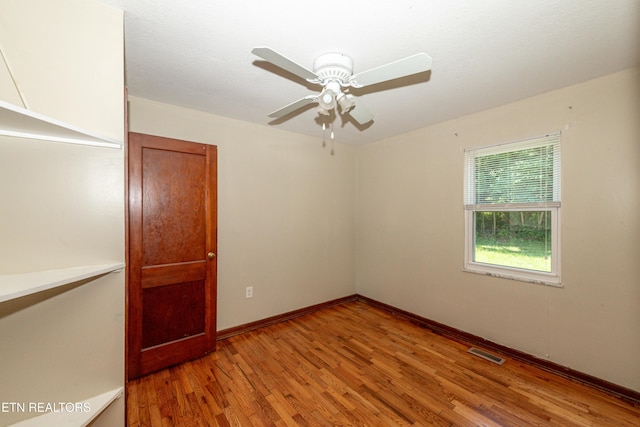 spare room with a ceiling fan, wood finished floors, visible vents, and baseboards