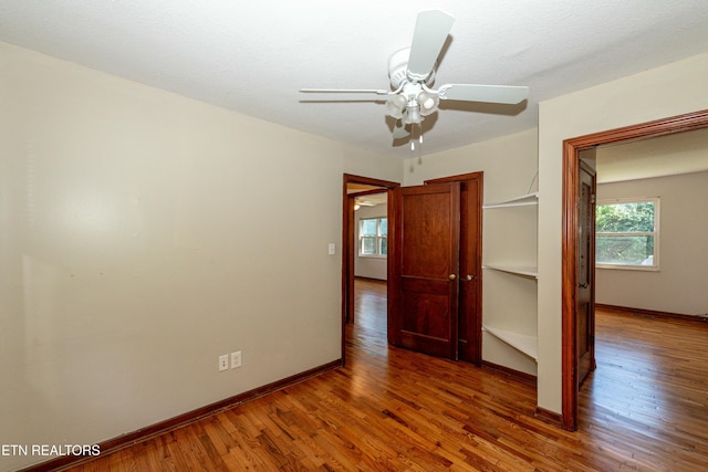 unfurnished bedroom with wood finished floors, a ceiling fan, and baseboards