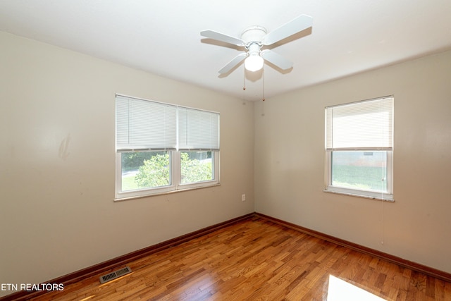 unfurnished room featuring light wood finished floors, baseboards, visible vents, and ceiling fan