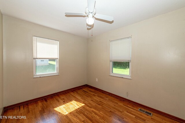 spare room with baseboards, ceiling fan, visible vents, and wood finished floors