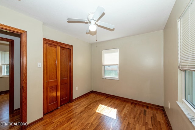 unfurnished bedroom featuring a ceiling fan, a closet, baseboards, and wood finished floors