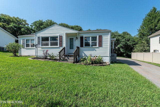 bungalow-style home with entry steps, driveway, fence, and a front lawn