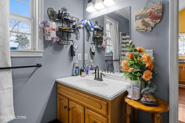 bathroom with a textured wall and vanity