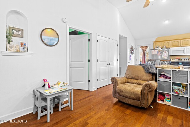 living area featuring high vaulted ceiling, wood finished floors, a ceiling fan, and baseboards