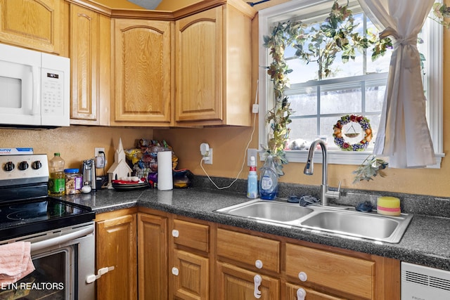 kitchen with dark countertops, white microwave, stainless steel electric range oven, and a sink