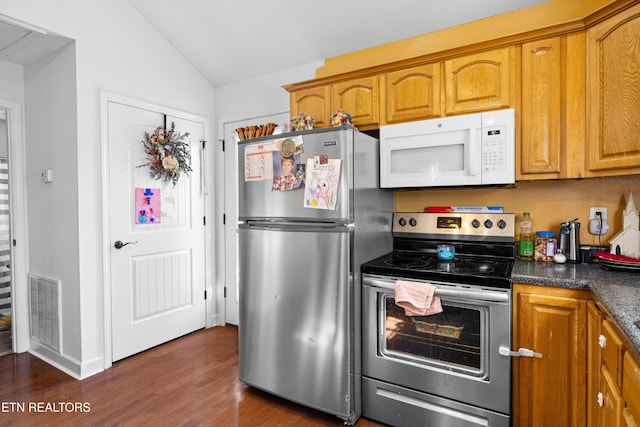 kitchen featuring lofted ceiling, visible vents, appliances with stainless steel finishes, dark wood-style floors, and dark countertops