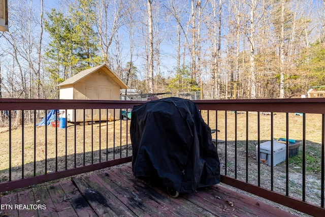 deck featuring area for grilling, a shed, and an outdoor structure