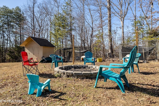exterior space featuring an outbuilding, fence, a fire pit, and a storage shed