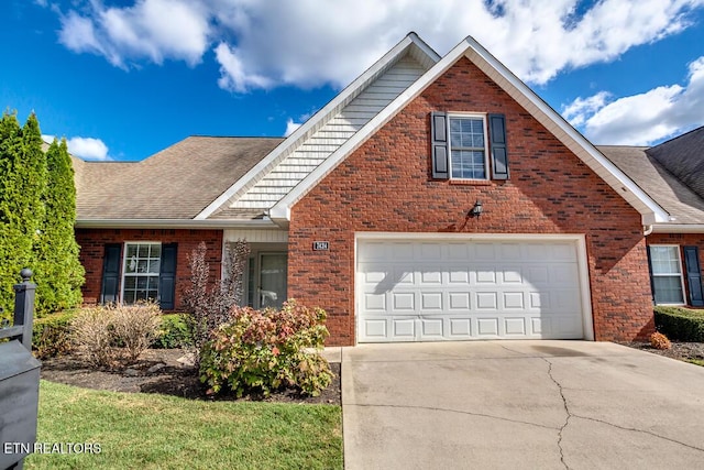 traditional-style house with a garage, brick siding, driveway, and a shingled roof