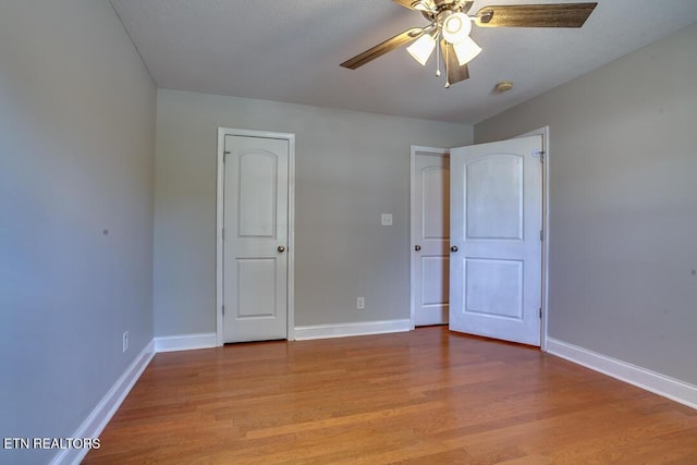 unfurnished bedroom with a ceiling fan, light wood-style flooring, and baseboards