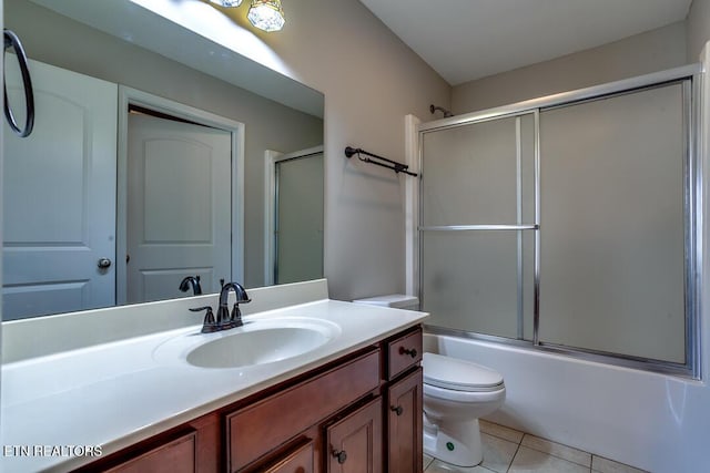 bathroom with combined bath / shower with glass door, vanity, toilet, and tile patterned floors