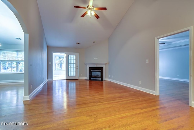 unfurnished living room featuring visible vents, light wood finished floors, a fireplace with flush hearth, and a wealth of natural light