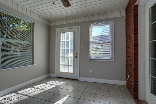 doorway with a ceiling fan, baseboards, and light tile patterned floors