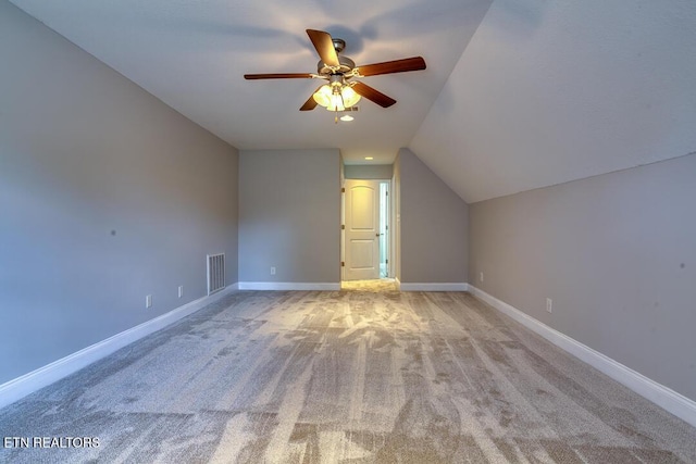 bonus room featuring lofted ceiling, light colored carpet, visible vents, ceiling fan, and baseboards