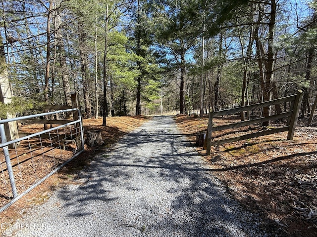 view of road with a gated entry and a wooded view