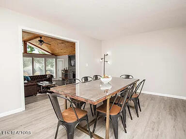 dining area featuring lofted ceiling, light wood-style flooring, and baseboards