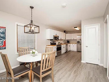 dining room with dark wood-style floors, a notable chandelier, and baseboards