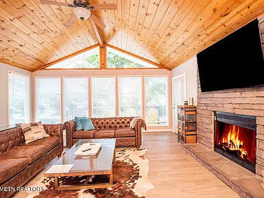 living area featuring lofted ceiling with beams, wooden ceiling, a fireplace, and wood finished floors