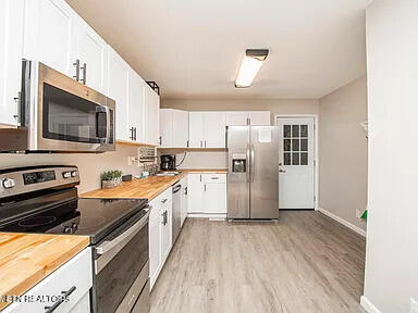 kitchen featuring stainless steel appliances, white cabinets, and wood counters