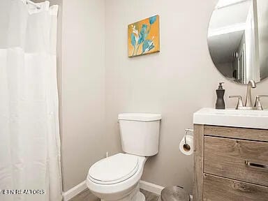 bathroom with toilet, vanity, and baseboards