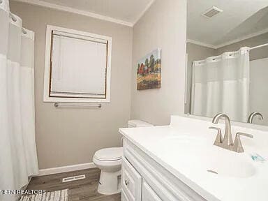 bathroom featuring visible vents, toilet, ornamental molding, vanity, and wood finished floors