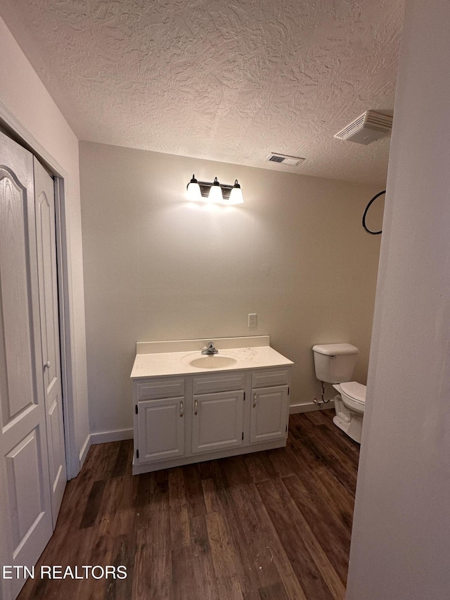 bathroom featuring visible vents, toilet, wood finished floors, a textured ceiling, and vanity