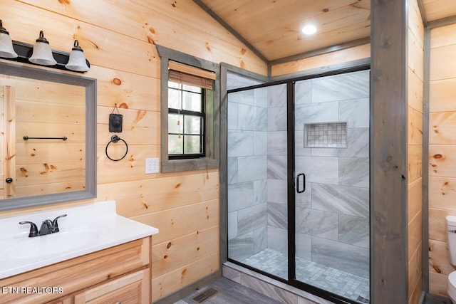 full bathroom with a stall shower, toilet, lofted ceiling, vanity, and wood walls