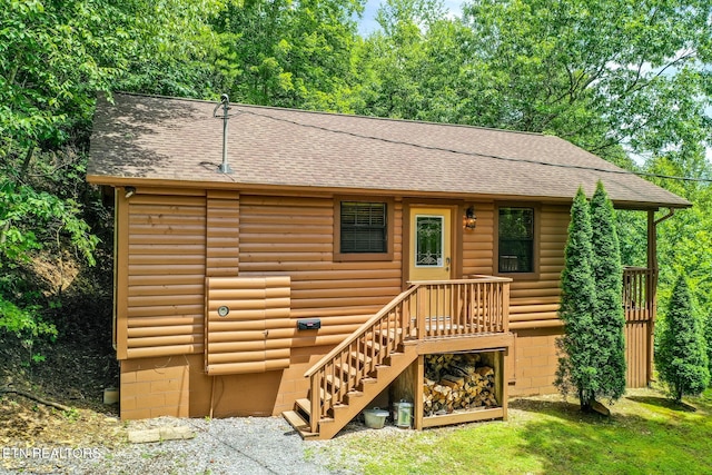 view of front of house with roof with shingles and faux log siding