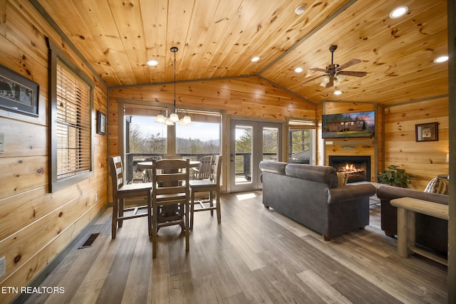 dining area featuring lofted ceiling, wooden ceiling, wooden walls, and wood finished floors