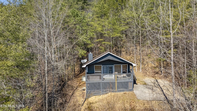 view of front of house with a chimney and a wooded view