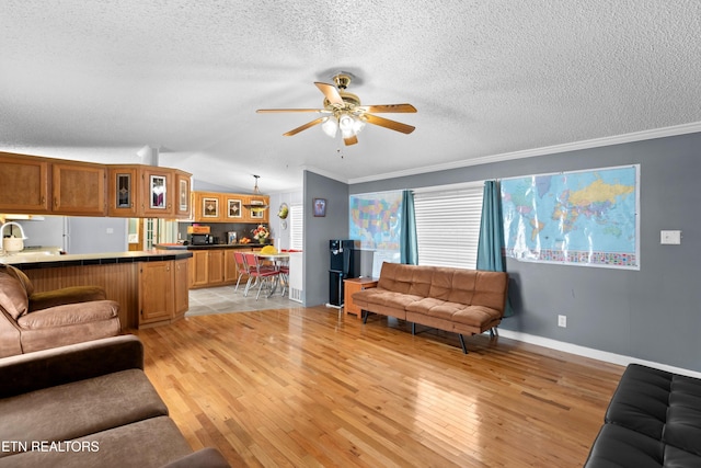 living area with a ceiling fan, light wood-style flooring, ornamental molding, vaulted ceiling, and a textured ceiling