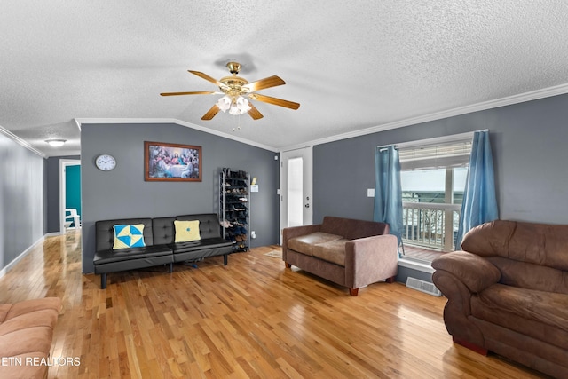 living area featuring lofted ceiling, ornamental molding, visible vents, and light wood-style floors