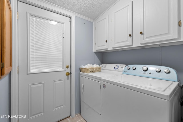 laundry room featuring cabinet space, a textured ceiling, and washing machine and clothes dryer