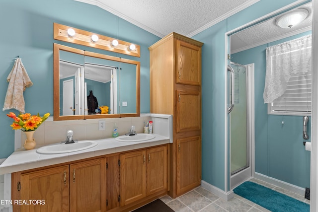 bathroom with a stall shower, a textured ceiling, ornamental molding, and a sink