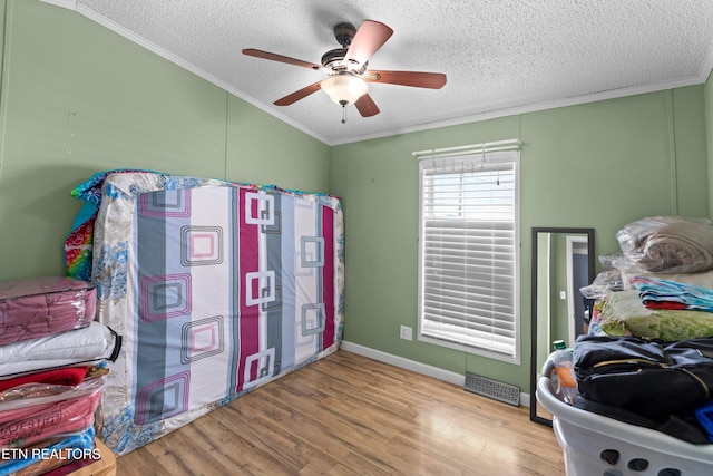 bedroom with a textured ceiling, ornamental molding, and wood finished floors