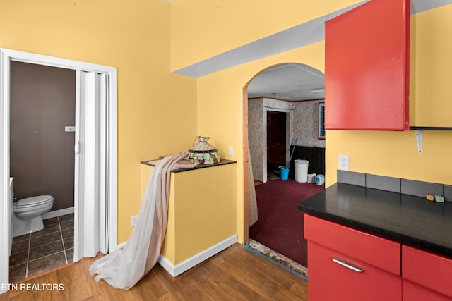 bathroom with toilet, baseboards, and wood finished floors