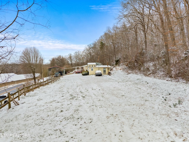 snowy yard with a detached garage and fence