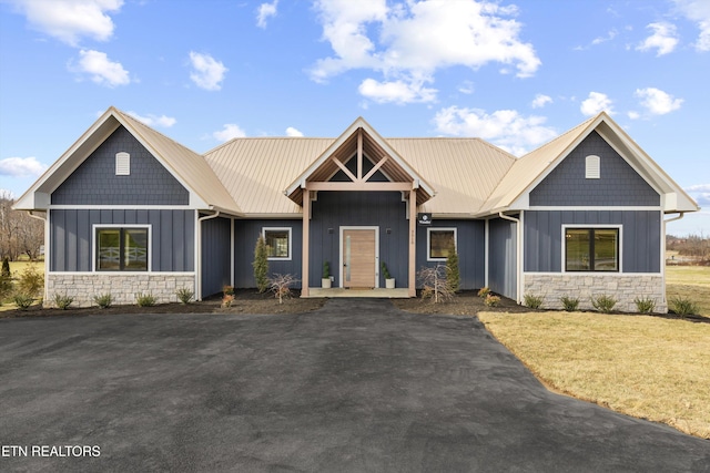 craftsman house featuring driveway, stone siding, and board and batten siding