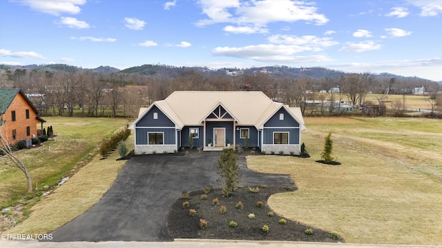 view of front of property featuring stone siding, aphalt driveway, and a front yard